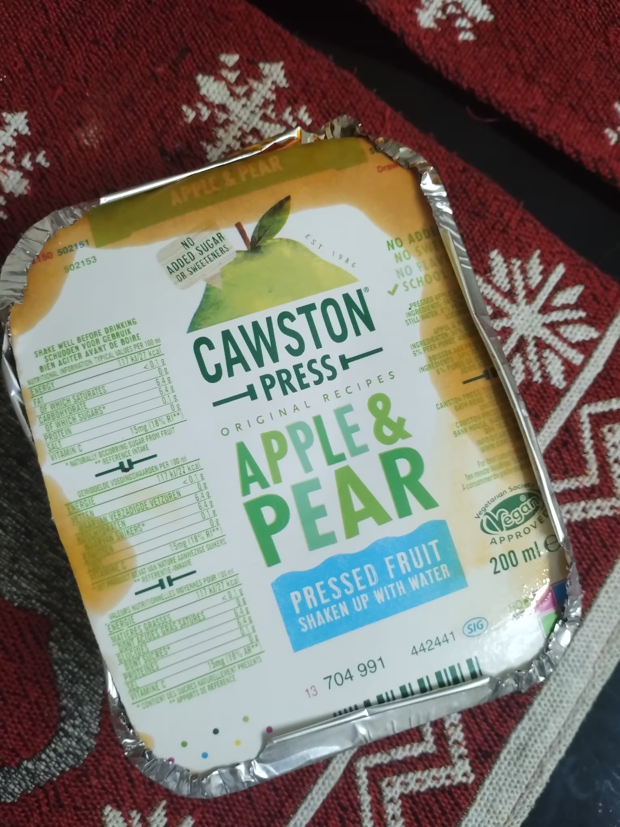Kerala beef (cooked) bought from roadside shop packaged in a flexible aluminium can like thing. The top of the can is covered by a plastic material used in milk carton like material, and features the following printed text:

Cawston Press
Apple & Pear
Pressed fruit
shaken up with water

Other details of the original product, such as "200 ml" and "vegetarian society vegan approved" can be seen on the cover.
