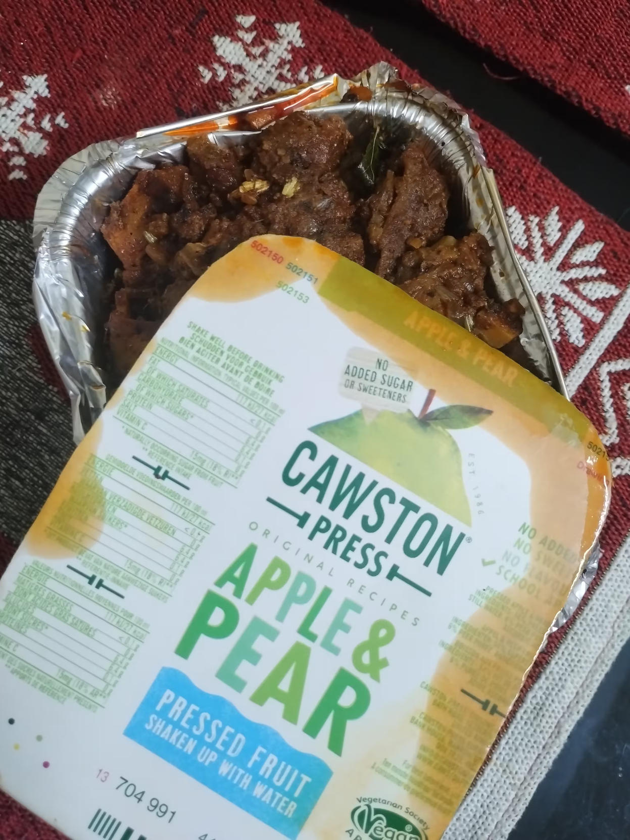 Kerala beef (cooked) bought from roadside shop packaged in a flexible aluminium can like thing. The top of the can, which is slightly open to show the cooked beef inside, is covered by a plastic material used in milk carton like material, and features the following printed text:

Cawston Press
Apple & Pear
Pressed fruit
shaken up with water

Other details of the original product, such as "vegetarian society vegan approved" can be seen on the cover.
